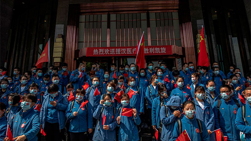Los trabajadores médicos chinos en una ceremonia antes de salir de Wuhan.
