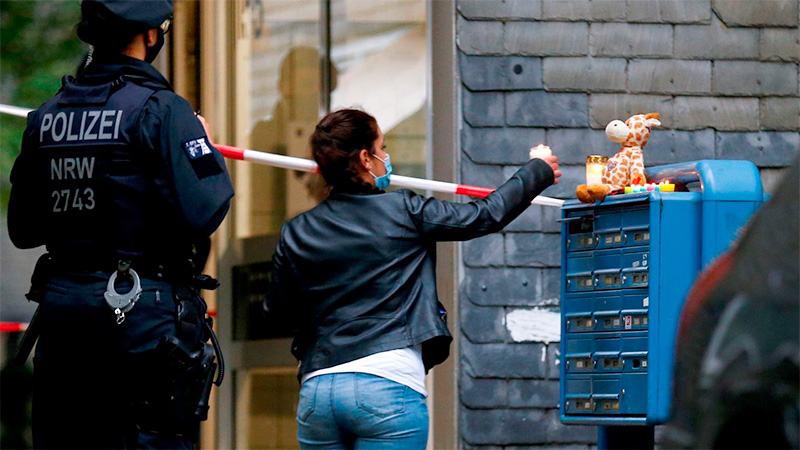 Una mujer prende una vela en la puerta del edificio.