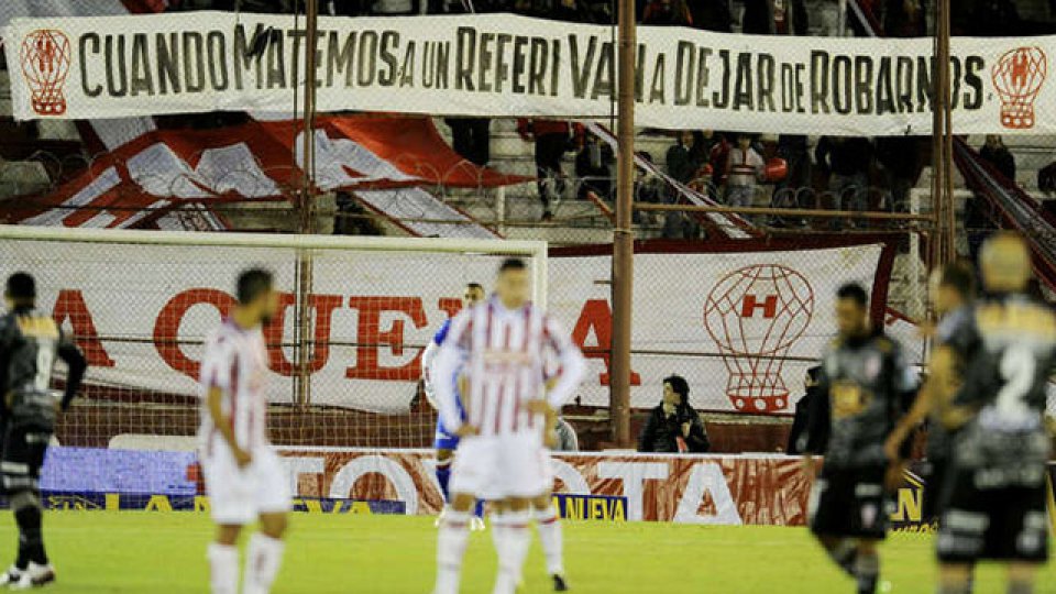 El árbitro Paletta paró el partido para que los barras bajen la bandera.