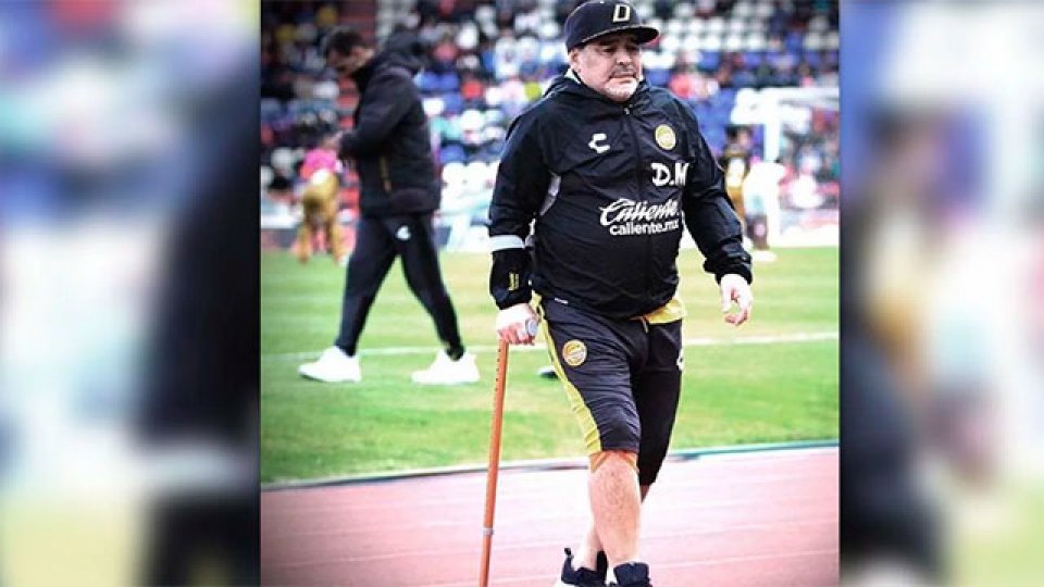 Maradona entró con bastón y necesitó ayuda para caminar.