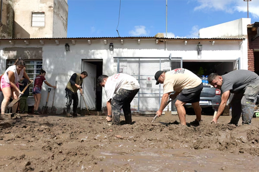 Bahienses trabajan en el frente de una casa para remover la tierra acumulada por la inundación
