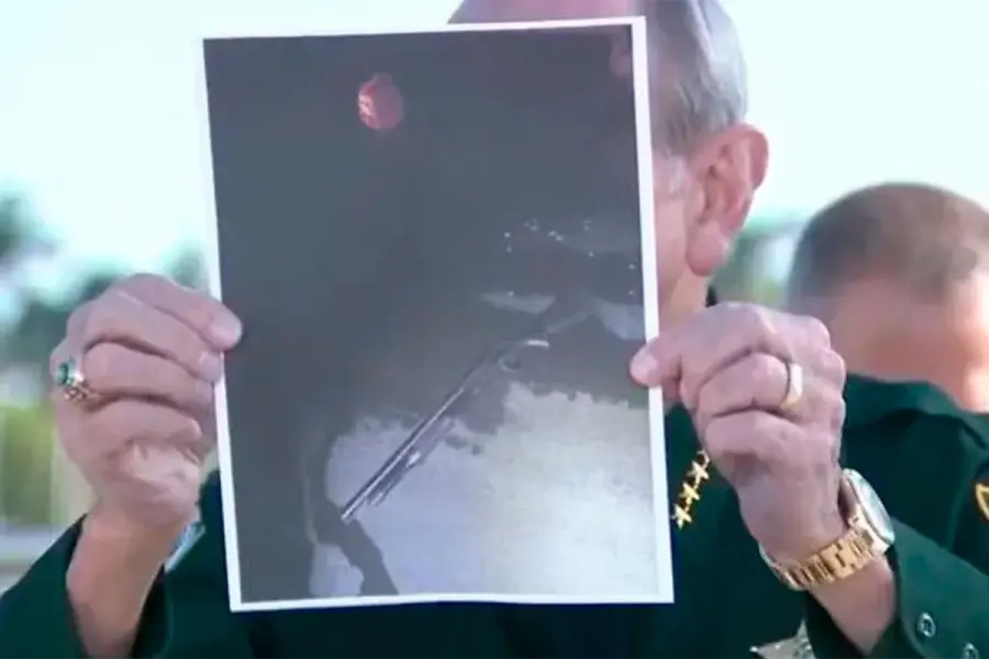 El sheriff del condado de Palm Beach, Ric Bradshaw, muestra una fotograf&iacute;a de la escopeta del sospechoso, con un bote de gasolina rojo visible en el fondo.