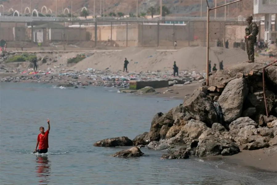 Un migrante de Marruecos camina por el agua tras cruzar a Ceuta por mar (foto Reuters)