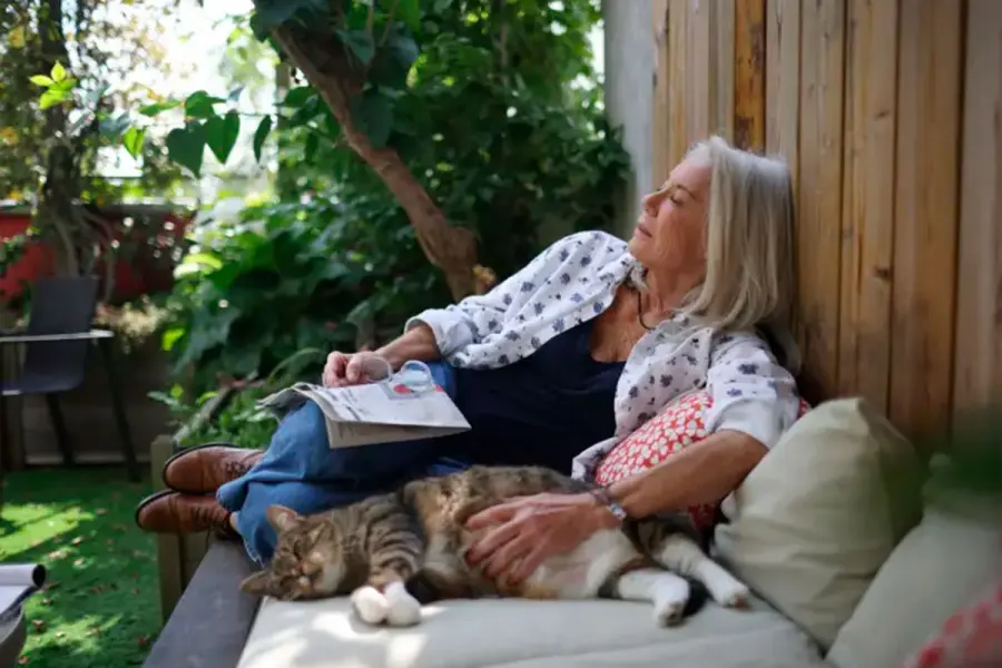 Una mujer durmiendo la siesta en su patio junto a su gato. (Foto: Getty Images).